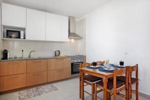 eine Küche mit Holzschränken und einem Tisch mit Stühlen in der Unterkunft A O - Augusta in Peniche