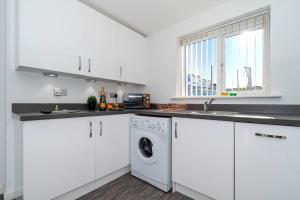 a kitchen with white cabinets and a washer and dryer at Detached 3 Bedroom House - Gaerden - Parking - Top Rated - Netflix - Wifi - 98C in Birmingham