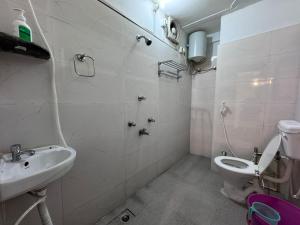 a white bathroom with a toilet and a sink at Hotel Nalanda Inn Bihar in Nalanda