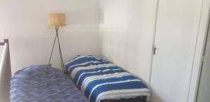 - un coin d'une chambre avec un lit et une lampe dans l'établissement Maison en pierres à 1200m de la mer, à Agon-Coutainville