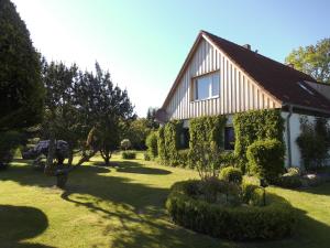 ein Haus in einem Garten mit Büschen und Bäumen in der Unterkunft Bungalow und Ferienwohnung auf Rügen in Kluis