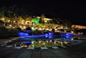 een zwembad 's nachts met blauwe lichten bij Indismart Woodbourne Resort in Madgaon