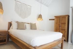 1 dormitorio con 1 cama grande con sábanas blancas en Villa Pagu, en Seminyak
