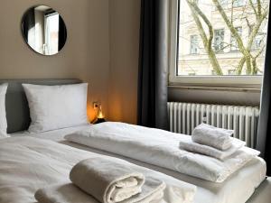 a bedroom with two beds with towels on them at Hotel Sendlinger Tor in Munich