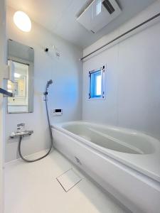 a white bathroom with a tub and a window at REGNO COMFORT ASAKUSA Ⅳ in Tokyo