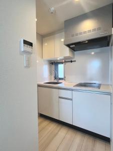 a kitchen with white cabinets and a sink at REGNO COMFORT ASAKUSA Ⅳ in Tokyo