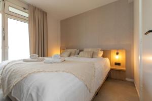 - une chambre avec un grand lit et des serviettes dans l'établissement Appartement - Nieuwstraat 1 - Zoutelande 'Kurhaus - 4 met sauna', à Zoutelande