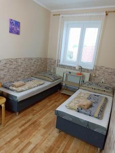 a room with two beds and a table and two windows at Abturist penzion in Štúrovo