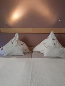 a bed with three pillows on top of it at Fewo Zum Sonnenschein in Simmerath