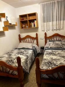 a bedroom with two beds and a book shelf at Apartamento a primera línea de Mar in Pineda de Mar