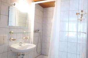 a white bathroom with a sink and a shower at City Garni in Martigny-Ville