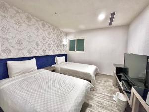 Habitación de hotel con 2 camas y TV de pantalla plana. en Walker Hotel - Zhengyi en Taipéi