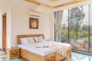 a bedroom with a bed and a large window at ELIVAAS 3 BHK with Treehouse & Pvt Pool - Handa's Gateway in Dhauj +48 photos