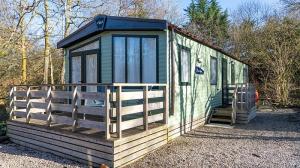 a green tiny house sitting on top of gravel at Newby Bridge Country Caravan Park in Newby Bridge