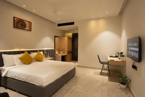 a bedroom with a bed and a desk and a tv at Hotel Kyzen Hi Tech City in Hyderabad