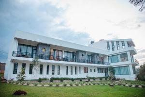 un grand bâtiment blanc avec une pelouse devant lui dans l'établissement Vista Heights Residence, à Kigali