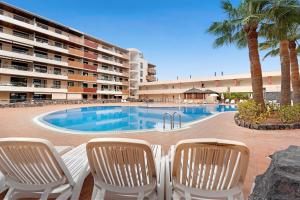 a swimming pool with two chairs and a hotel at Balcón de Los Gigantes in Puerto de Santiago