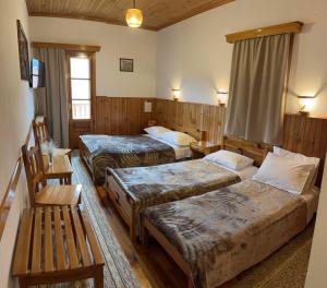 une chambre d'hôtel avec trois lits et un banc dans l'établissement HOTEL MARI Metsovo, à Metsovo
