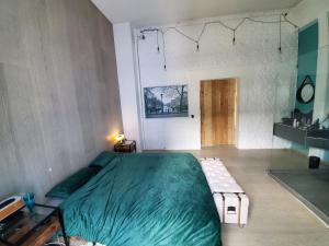 a bedroom with a large green bed and a table at Stunning Industrial Loft in a former Power Plant in Essen