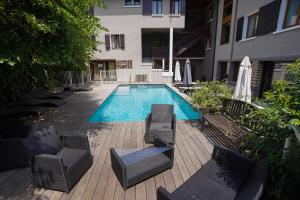 a swimming pool with chairs and umbrellas next to a building at Auberge Le Semnoz in Saint-Jorioz