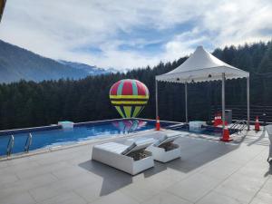 uma piscina com um balão de ar quente e uma tenda em The Orchard Greens Resort - A Centrally Heated Property em Manali