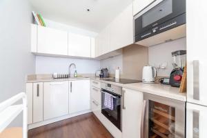 een keuken met witte kasten en een wastafel bij Cosy Central Urban Retreat in Highbury & Islington in Londen