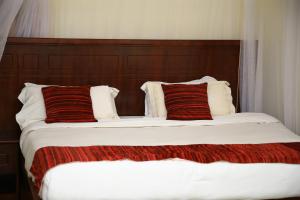1 dormitorio con 2 camas y almohadas rojas y blancas en GLORY SUMMIT HOTEL HOIMA, en Hoima