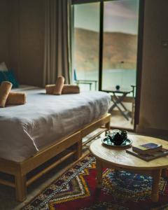 sypialnia z łóżkiem, stołem i lustrem w obiekcie The Moroccan Surf House w mieście Imsouane