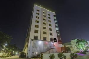 a tall white building is lit up at night at Palette - Hotel chennai le palace in Chennai