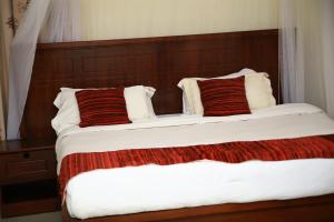 1 dormitorio con 2 camas y almohadas rojas y blancas en GLORY SUMMIT HOTEL HOIMA, en Hoima