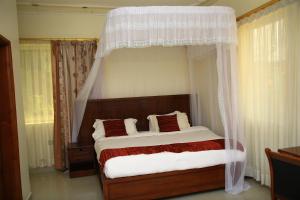 1 dormitorio con cama con dosel y cortinas blancas en GLORY SUMMIT HOTEL HOIMA, en Hoima