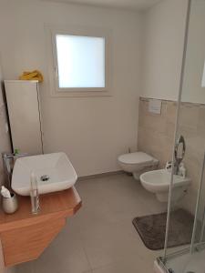 bagno bianco con lavandino e servizi igienici di Villetta Baia 1 a Golfo Aranci