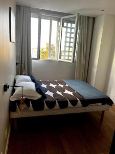 - une chambre avec un lit doté d'une couverture en damier et d'une fenêtre dans l'établissement Le Saint-Irénée, à Lyon