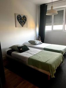 Le Saint-Irénée في ليون: سريرين في غرفة نوم مع صورة قلب على الحائط