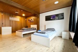 two beds in a room with wooden walls at Work&Stay Apartments Hellenthal in Hellenthal