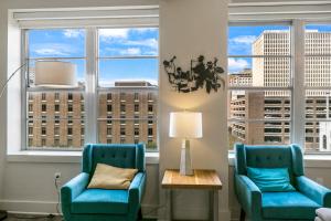 two chairs and a table in a room with windows at Spacious 4BR Luxury Condo Steps to French Quarter in New Orleans