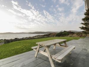 a wooden picnic table on a patio overlooking the water at Merse End in Dalbeattie