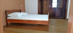 Cama pequeña en habitación con suelo de madera en Chambre D'hôtes Morondava en Morondava