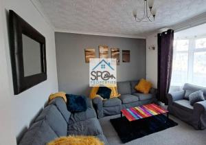 Modern 4BR Home-7 Guests-Business-Families-Netflix-Free Parking & WiFi في Pontnewynydd: غرفة معيشة مع أريكة رمادية وطاولة