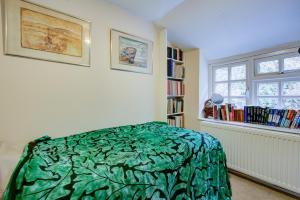 a bedroom with a green bed and a book shelf at Charming Hilltop Cottage with Panoramic Views in East Worldham