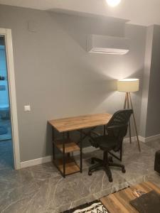 einen Schreibtisch in einem Zimmer mit einem Stuhl und einer Lampe in der Unterkunft Adana Centrum Flat 1 in Seyhan