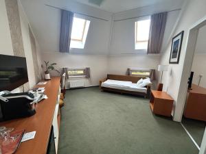 a room with a bed and a desk and windows at Boutique Hotel Sopianae in Pécs