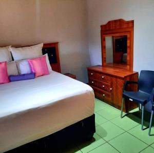 a bedroom with a bed and a dresser and a mirror at Mokopane at Freedom City Lodge in Mokopane