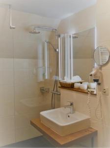 ein Bad mit einem Waschbecken und einer Dusche mit einem Spiegel in der Unterkunft Landhotel Restaurant Hubinger in Thörl