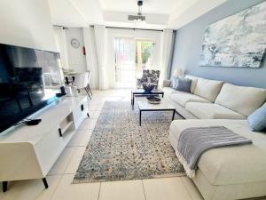 een woonkamer met een witte bank en een tv bij Private pool/Sleep 6/15 mins drive to beach/Marina in Dubai