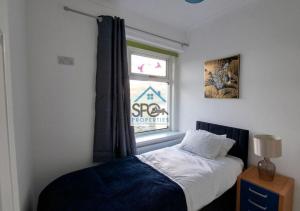 1 dormitorio con cama y ventana en Modern 4BR Home-7 Guests-Business-Families-Netflix-Free Parking & WiFi, en Pontnewynydd