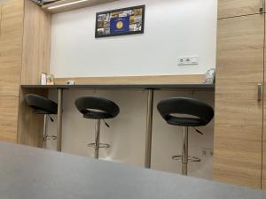 a counter with three black stools in a room at Tiny Apartments in Miskolc