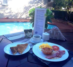 two plates of breakfast food on a table next to a pool at Pretoria East Guests in Pretoria