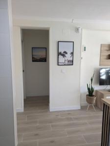 sala de estar con paredes blancas y suelo de madera. en Apartamento Torremar, en Alicante