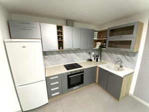 uma cozinha com armários brancos, um lavatório e um frigorífico em Skopje Sky Apartment 32nd floor em Skopje